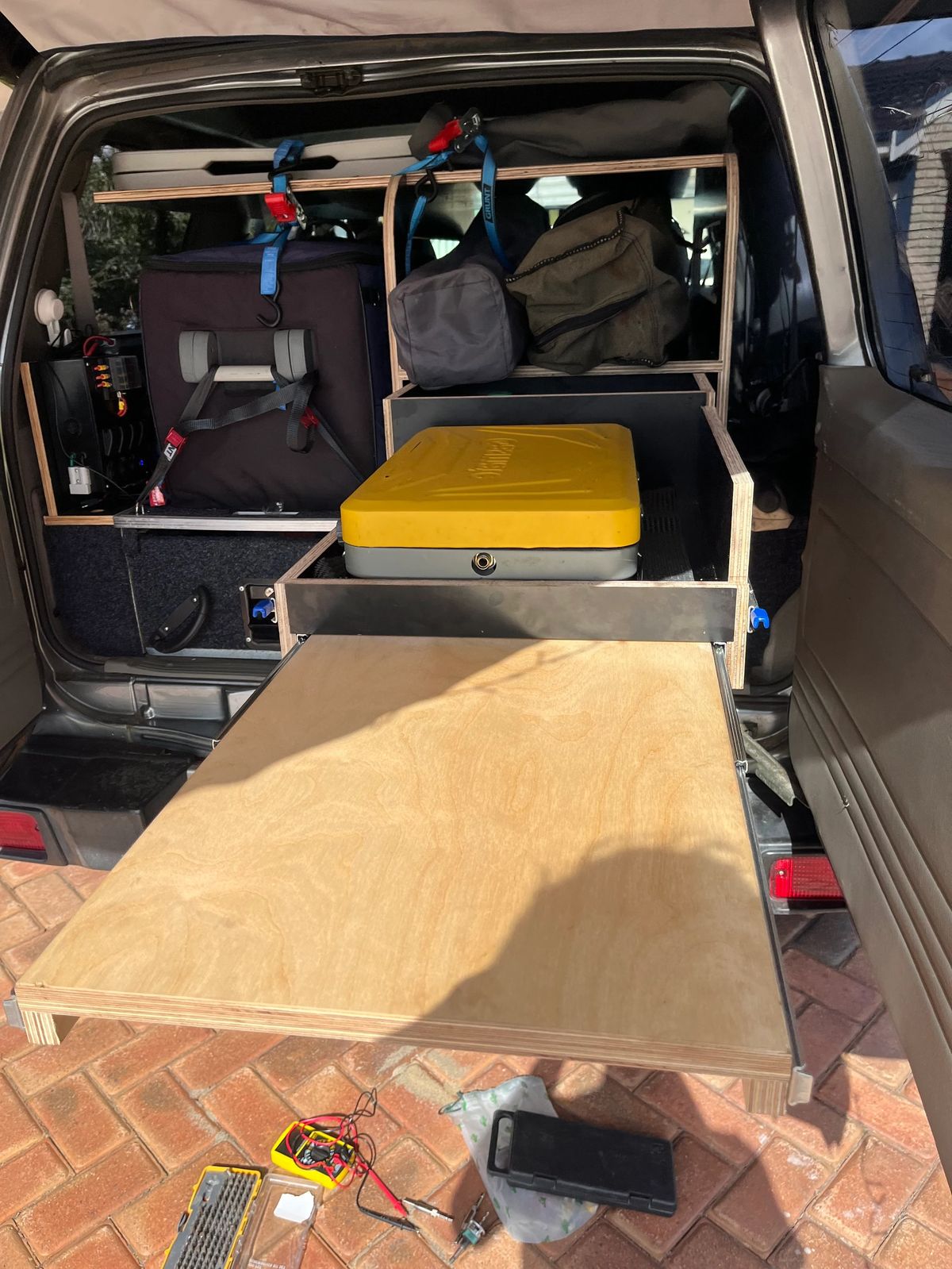 Plywood camper storage and a pull-out kitchen under construction in the Nissan Patrol.